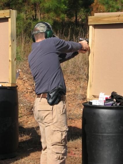 Defensive Shooting Class student firing from behind a barrel barricade